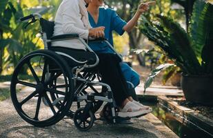 een verpleegster nemen zorg een senior mannetje Aan rolstoel in zijn tuin Bij huis foto