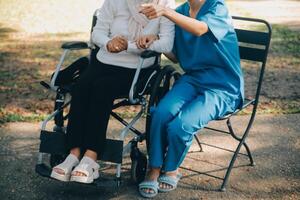 een verpleegster nemen zorg een senior mannetje Aan rolstoel in zijn tuin Bij huis foto