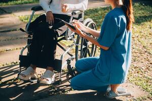 verpleging personeel pratend naar een ouderen persoon zittend in een rolstoel. foto