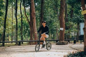 knap gelukkig jong Mens met fiets Aan een stad straat, actief levensstijl, mensen concept foto