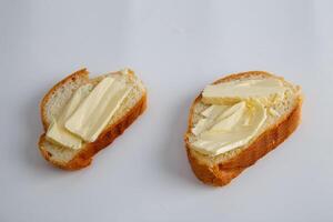 twee stukken van wit brood met boter Aan wit achtergrond foto
