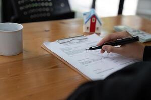 echt landgoed middel Holding pen naar zijn cliënt voor ondertekening overeenkomst, concept voor echt landgoed, in beweging huis of huren eigendom foto