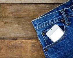 slim telefoon in zak- jeans Aan houten achtergrond foto