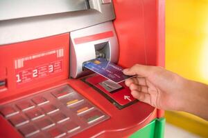 hand- invoegen met een credit kaart in bank machine . Mens gebruik makend van een Geldautomaat machine met credit kaart naar terugtrekken geld foto