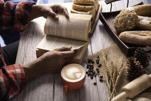 hand- Holding een kop van koffie en lezing een boek sleutel van succes - concept levensstijl foto