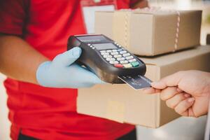 mannetje levering arbeiders slijtage sanitaire voorzieningen gezichten en slijtage handschoenen, leveren goederen of pakjes, levering onderhoud voor gebruikers naar betalen via credit kaart voor gemak en vergiffenis gedurende covid19. foto