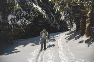 middelbare leeftijd cross-country skiër oud 50-55 maakt zijn eigen bijhouden in diep sneeuw in de wildernis in de ochtend- zonnig weer in beskydy bergen, Tsjechisch republiek foto