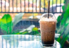ijs koffie in een hoog glas Aan een tafel. verkoudheid zomer drinken in koffie winkel foto
