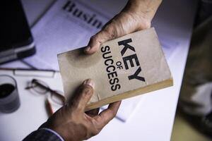 zakenlieden leveren de boek over de sleutels naar bedrijf succes - bedrijf samenwerking ideeën foto