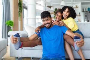 aantrekkelijk gelukkig familie knuffelen aantrekkelijk moeder knap vader en aanbiddelijk klein dochter zittend samen Aan bankstel in leven kamer Bij huis glimlachen op zoek Bij camera foto