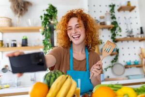 jong vrouw is in de keuken, ze heeft draadloze hoofdtelefoons Aan, ze is dansen en het zingen foto