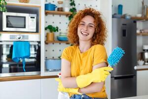 jong vrouw aan het doen huis klusjes Holding schoonmaak hulpmiddelen. vrouw vervelend rubber beschermend geel handschoenen, Holding vod en verstuiven fles wasmiddel. zijn nooit te laat naar schoon foto