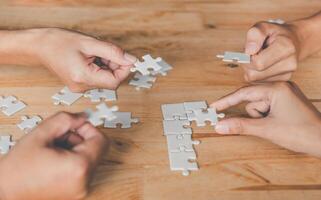 bedrijf team omgaan met een stuk van wit puzzels dat zijn over naar laten vallen naar krijgen een compleet werkblad - een poging naar slagen. foto