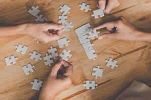 bedrijf team omgaan met een stuk van wit puzzels dat zijn over naar laten vallen naar krijgen een compleet werkblad - een poging naar slagen. foto