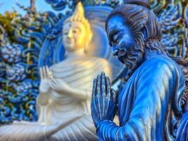 bidden monnik standbeeld Bij wat rong suea tien blauw tempel, Chiang rai, Thailand foto