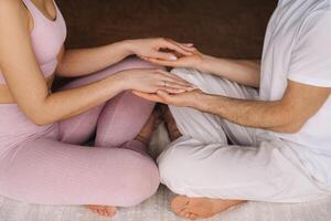 een vrouw en een Mens zijn verloofd in paar- meditatie Holding handen in de Sportschool foto