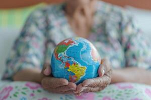 ai gegenereerd ouderen Aziatisch geduldig met wereldbol symboliseert Gezondheid in ziekenhuis. foto