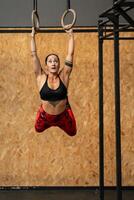 sportief vrouw hangende van olympisch ringen terwijl werken uit foto