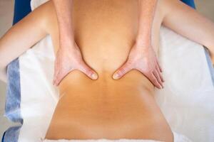 professioneel masseuse masseren terug van vrouw gedurende fysiotherapie sessie foto