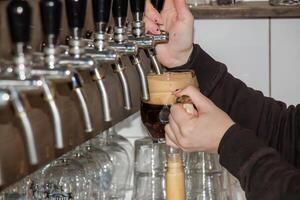 achter de balie. vrouwen handen prachtig en gemakkelijk gieten bier in een fles. foto