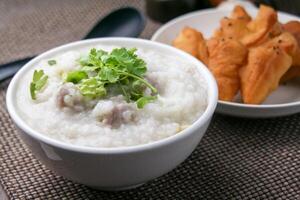 dichtbij omhoog rijst- pap , congee met fijngehakt varkensvlees en gember in wit kom foto