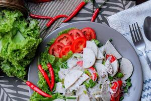 pittig glas noodle salade met Vietnamees worst geserveerd in een grijs bord zetten Aan een houten tafel en divers groenten. foto