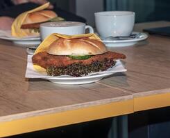 hamburger met vers salade, kaas en kotelet en een kop van koffie Aan een houten tafel. foto