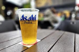 yufuin, Japan november 12, 2023 asahi bier Aan houten tafel, zijn een beroemd Japans super droog bier en gedistribueerd door asahi brouwerijen, ltd. foto