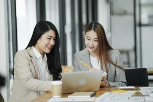 twee bedrijf Dames zijn bespreken de werk ze hebben gedaan samen en uitwisselen ideeën. naar werk naar ontwikkelen de bedrijf beter. foto