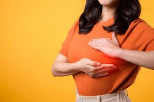 machtigen gezondheidszorg Aan wereld Gezondheid dag, net zo een vrouw cheques voor borst kanker tekens met handen Aan geel achtergrond. foto