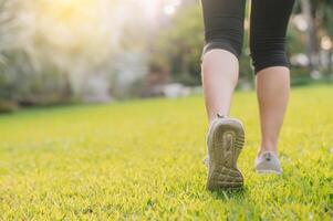 jogger vrouw. dichtbij omhoog persoon opleiding sport loper jong vrouw schoen Aan grassen in openbaar park. geschiktheid been en voet oefening atleet. marathon in natuur. actief gezond levensstijl training concept. foto