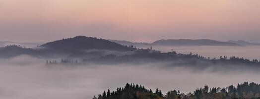 panoramisch mistig landschap Bij dageraad over- berg en vallei foto
