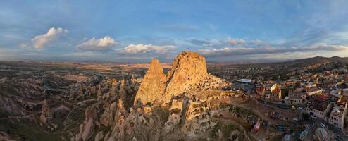 antenne panoramisch visie van de uchisar kasteel in Cappadocië, kalkoen gedurende zonsondergang. deze hoog vulkanische rots ontsluiting is een van cappadocië meest prominent oriëntatiepunten. foto