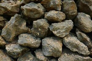 gestapeld rotsen textuur, gedetailleerd structuur van een steen fundament ondersteunen grind gevelbekleding foto