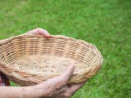 detailopname van senior vrouw handen Holding leeg rieten mand in haar tuin foto