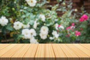 leeg hout tafel top met vervagen roos tuin achtergrond voor Product Scherm foto