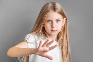 een weinig meisje tonen een teken van protest of weigering met haar hand. foto