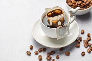 druppelen koffie zak met grond koffie in kop foto