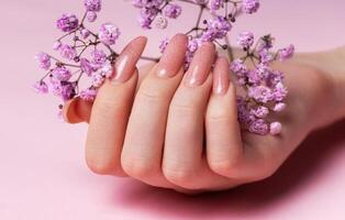 vrouw handen met roze nagel ontwerp houden gypsophila bloemen. foto