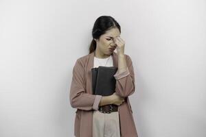 een benadrukt jong Aziatisch leerling vervelend Cardigan terwijl Holding boeken, geïsoleerd door wit achtergrond. foto