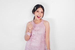aantrekkelijk jong Aziatisch vrouw in roze jurk is gebaren duimen omhoog foto