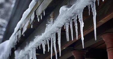 ai gegenereerd doordringend ijspegels en sneeuw aambeien vastklampen naar een grijs dak, complementair een plafond lamp en steen muur foto