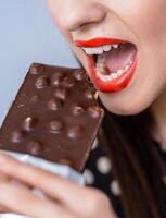 vrouw genieten van een chocola bar. een vrouw aan het eten een chocola bar met haar mond Open foto