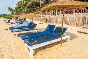 kleurrijk houten strand paraplu's en ligbedden ligstoelen Aan zanderig strand van oceaan foto