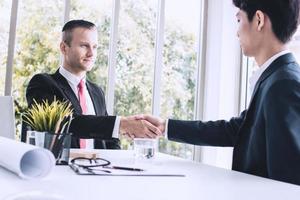 zakenmensen onderhandelen en schudden elkaar de hand na een succesvolle overeenkomst
