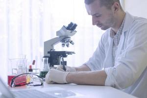 wetenschapper experiment chemische vloeistof en schrijven van informatie op papier in laboratorium