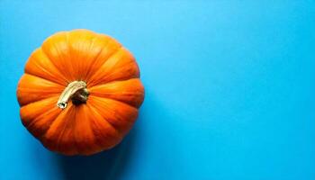 ai gegenereerd een single oranje pompoen Aan een blauw achtergrond foto