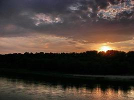 zonsondergang boven de rivier in natuurlijk landelijk landschap foto