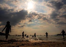 silhouetten van mensen die in de zee spelen op een openbaar strand foto