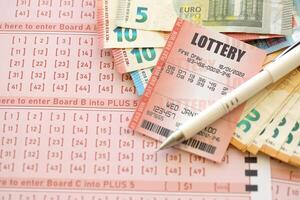 loterij ticket en het gokken bon Aan tafel met pen en Europese unie euro geld rekeningen foto